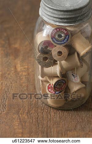 Stock Photo - Jar of thread and reels on table. Fotosearch