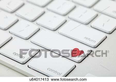 Stock Image - Keyboard with red heart on button, close-up. Fotosearch