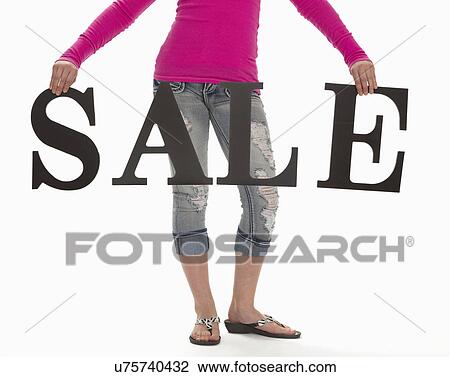 Stock Image - Low section of young woman holding sale sign. Fotosearch