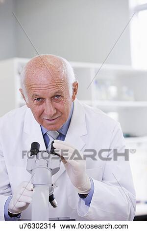 Picture - Male scientist using microscope in laboratory, portrait. Fotosearch