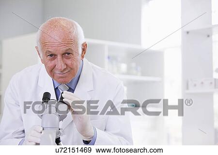 Stock Photo - Male scientist using microscope in laboratory, portrait. Fotosearch