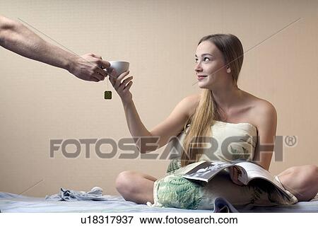 Man handing cup of tea to young woman sitting on bed View Large Photo Image Stock Photo - Man handing cup of tea to young woman sitting on bed. Fotosearch