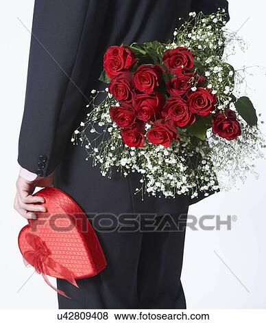 Stock Photo - Man holding bouquet and Valentine's gift . Fotosearch