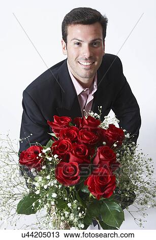 Stock Image - Man holding bouquet of roses, portrait. Fotosearch
