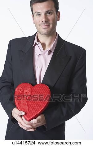 Picture - Man holding heart shape box, portrait. Fotosearch