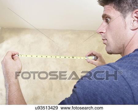 Man looking at measuring tape View Large Photo Image Stock Photo - Man looking at measuring tape. Fotosearch