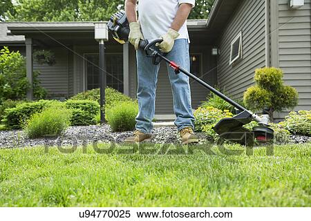 Stock Photography - Man mowing grass in back yard. Fotosearch