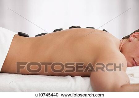 Stock Image - Man receiving la stone therapy. Fotosearch