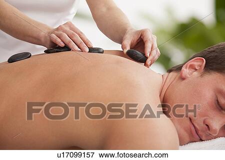 Stock Photo - Man receiving la stone therapy. Fotosearch
