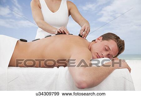 Stock Photo - Man receiving la stone therapy. Fotosearch