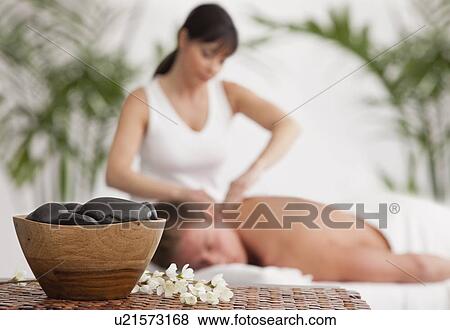 Stock Photo - Man receiving massage, stones in bowl in foreground. Fotosearch