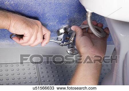 Stock Image - Man repairing toilet, close-up. Fotosearch