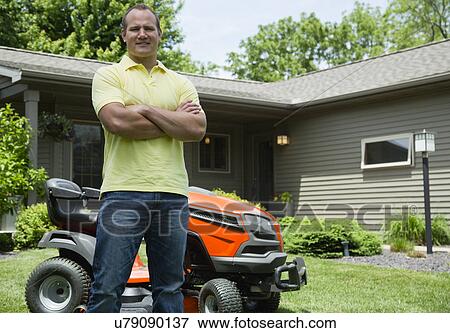 Stock Photo - Man standing in front of lawn mower . Fotosearch