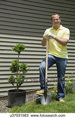 Man with shovel standing in front of house View Large Photo Image Stock Image - Man with shovel standing in front of house. Fotosearch