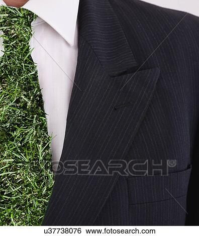 Stock Photograph - Man with tie covered by grass pattern, studio shot. Fotosearch