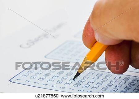 Stock Image - Man writing on college exam form. Fotosearch