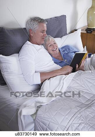 Mature couple reading book in bed View Large Photo Image Stock Photo - Mature couple reading book in bed. Fotosearch