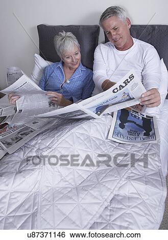 Mature couple reading newspapers in bed View Large Photo Image Stock Photograph - Mature couple reading newspapers in bed. Fotosearch
