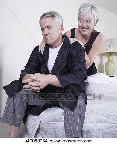Picture - Mature woman consoling man sitting on bed. Fotosearch