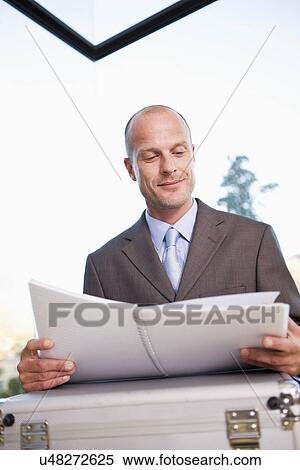 Mid adult businessman reading file, smiling View Large Photo Image Stock Photography - Mid adult businessman reading file, smiling. Fotosearch