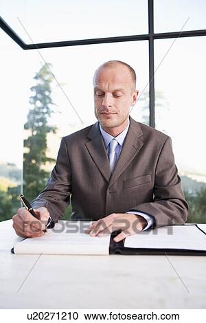 Stock Image - Mid adult businessman signing document. Fotosearch