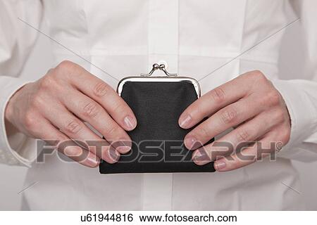 Stock Photograph - Mid adult woman holding purse, studio shot. Fotosearch