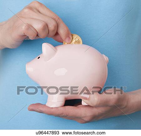 Mid adult woman putting coin into piggybank, studio shot View Large Photo Image Stock Image - Mid adult woman putting coin into piggybank, studio shot. Fotosearch
