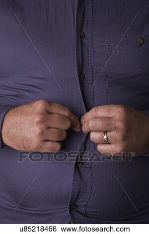 Mid section of man buttoning up shirt View Large Photo Image Stock Photograph - Mid section of man buttoning up shirt. Fotosearch