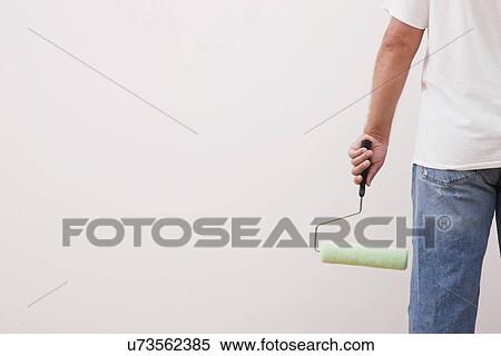Stock Photography - Mid section of man with paint roller. Fotosearch
