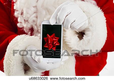 Stock Photograph - Mid section of Santa holding cell phone. Fotosearch