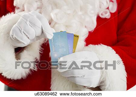 Stock Image - Mid section of Santa holding credit cards. Fotosearch