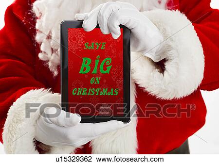 Stock Image - Mid section of Santa holding digital tablet. Fotosearch