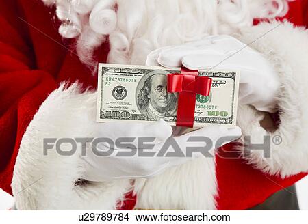 Picture - Mid section of Santa holding paper currency tied with ribbon. Fotosearch