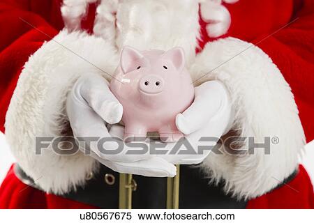 Stock Photography - Mid section of Santa holding piggy bank. Fotosearch
