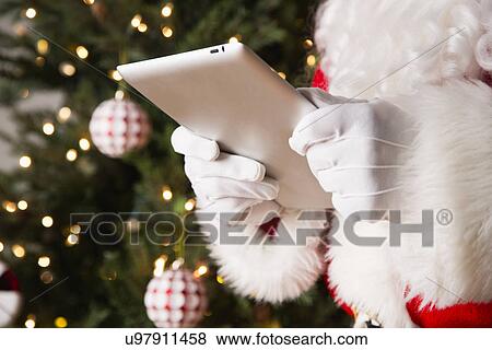 Mid section of Santa using digital tablet View Large Photo Image Stock Photo - Mid section of Santa using digital tablet. Fotosearch
