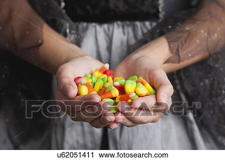 Stock Image - Midsection of teen girl holding handful of candies. Fotosearch