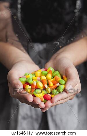 Stock Photo - Midsection of teen girl holding handful of candies. Fotosearch