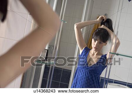 Mirror reflection of young woman doing hair in bathroom View Large Photo Image Stock Image - Mirror reflection of young woman doing hair in bathroom. Fotosearch