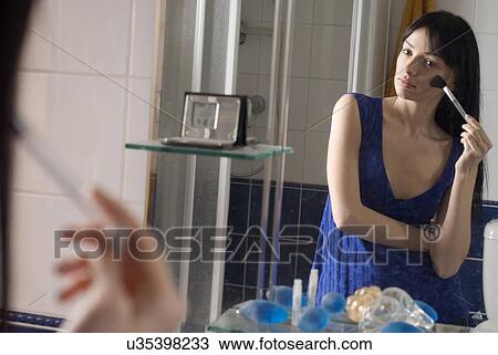 Mirror reflection of young woman applying make up in bathroom View Large Photo Image Stock Image - Mirror reflection of young woman applying make up in bathroom. Fotosearch