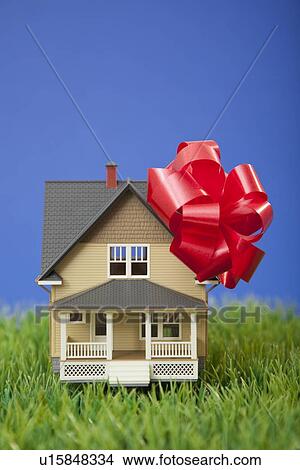 Picture - Model house with red ribbon on grass. Fotosearch