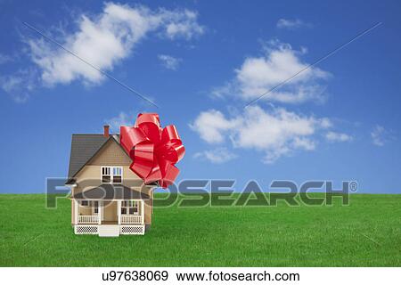 Stock Photo - Model house with red ribbon on grass. Fotosearch