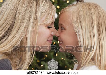 Picture - Mother and daughter (6-7) touching bonzes in front of Christmas tree. Fotosearch
