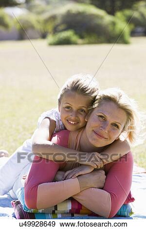 Stock Photo - Mother and daughter (8-9) embracing in park, portrait. Fotosearch