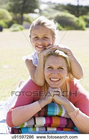 Stock Photograph - Mother and daughter (8-9) embracing in park, portrait. Fotosearch