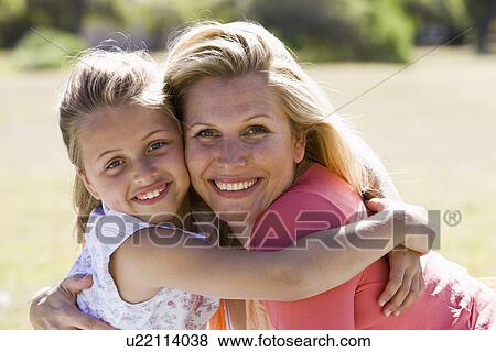 Stock Photo - Mother and daughter (8-9) embracing, portrait. Fotosearch