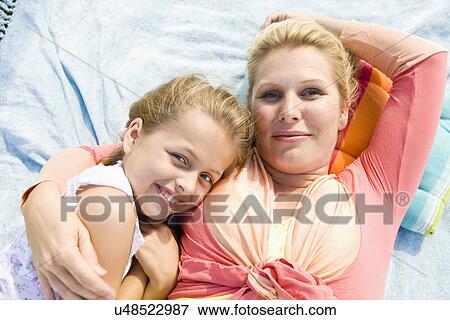 Stock Photo - Mother and daughter (8-9) embracing, portrait. Fotosearch
