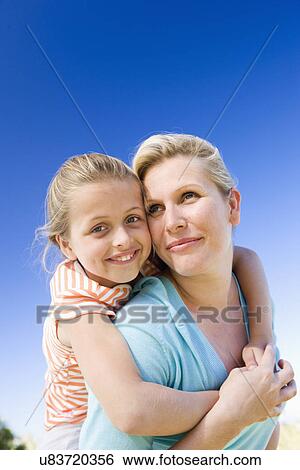 Stock Photograph - Mother carrying daughter (8-9) on shoulders. Fotosearch