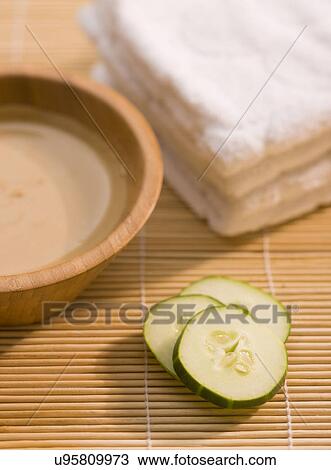 Stock Image - Mud mask and slices of cucumber on bamboo mat. Fotosearch