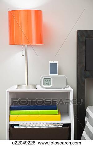 Stock Photograph - Night table next to bed in dorm room. Fotosearch