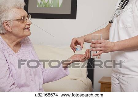Nurse giving pills to senior patient, close-up View Large Photo Image Picture - Nurse giving pills to senior patient, close-up. Fotosearch